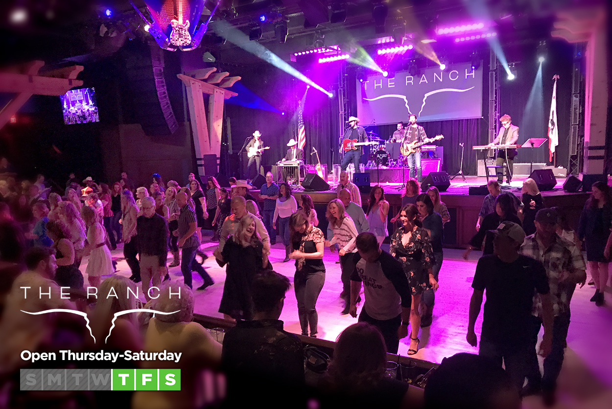 Live country band on stage with a dance floor full of line dancers at The Ranch Saloon